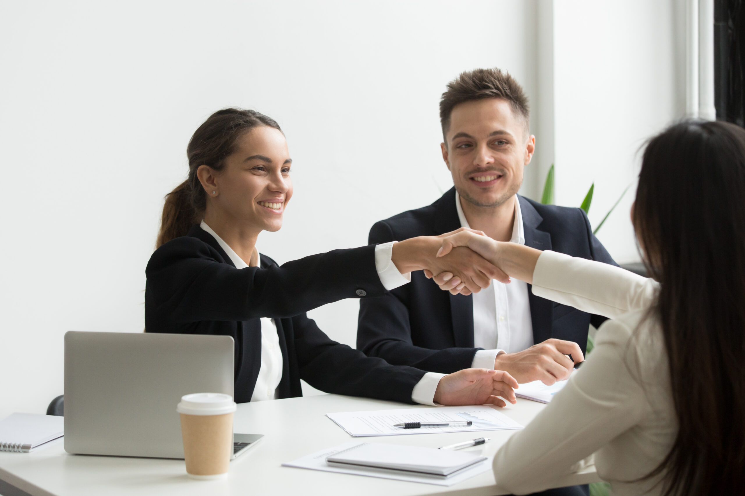 Smiling HR managers greeting female job applicant with handshake during recruiting or interview. Businesswoman making good first impression shaking hands of business partners. Partnership, cooperation